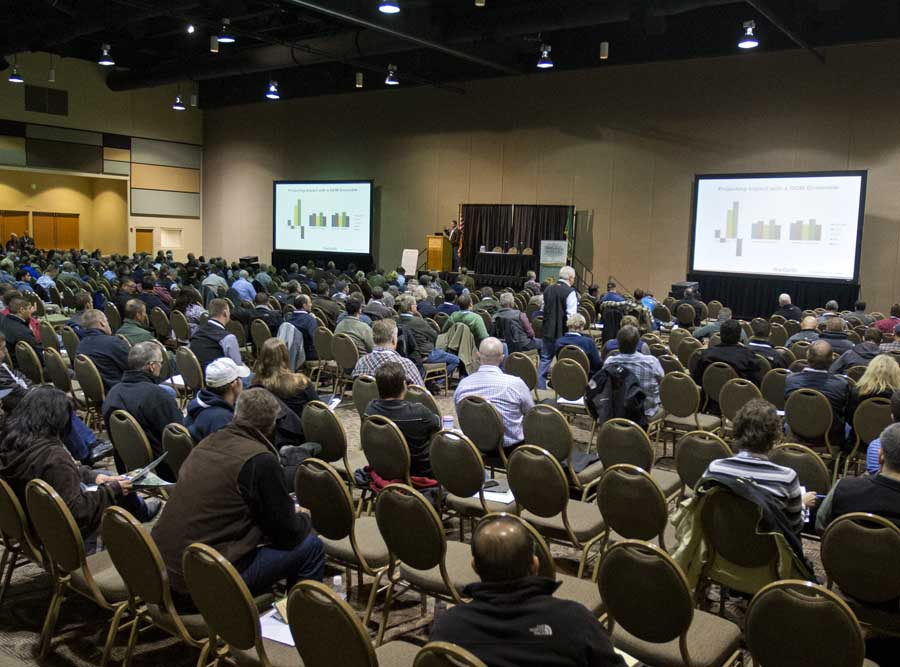 Conference room with people listening to a speaker on stage