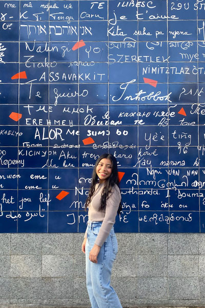 woman stands in front of Le Mur des Je t'aime, or the Wall of Love, in the Montmartre neighborhood of Paris