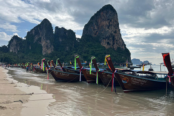 Thai longtail boats lined up on the shore of Railay Beach, a popular coastal site in southern Thailand