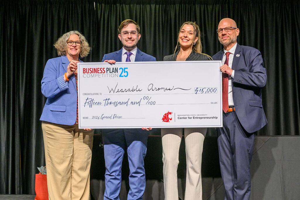Four people stand on stage holding an oversized check for $15,000 made out to Wearable Aromas, awarded as the 2025 Business Plan Competition grand prize by the WSU Center for Entrepreneurship.