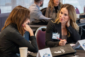 Two participants seated at a table during the Tri-Cities One Hanford Leadership Academy, engaged in discussion with notebooks and event materials in front of them.