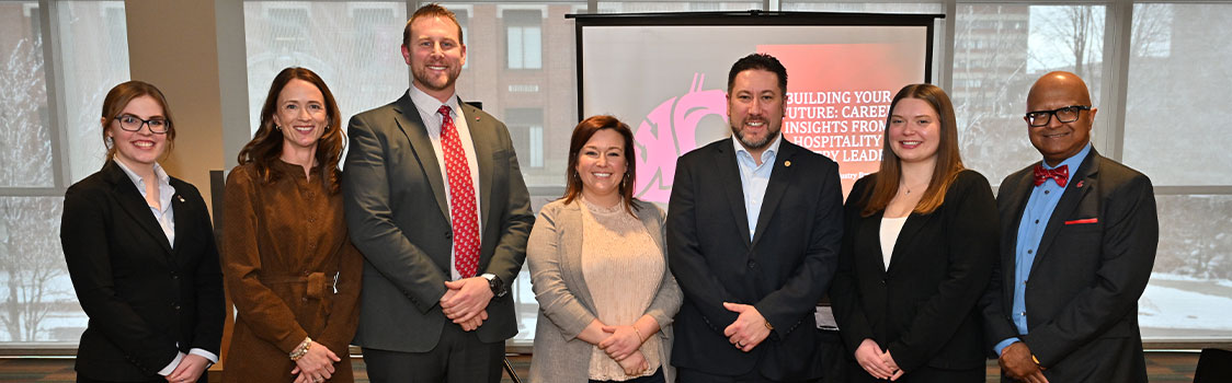 Group of professionally dressed individuals standing in front of a presentation screen displaying the text “Building Your Future: Career Insights from Hospitality Industry Leaders” during the Hospitality Week Industry Expert Panel.