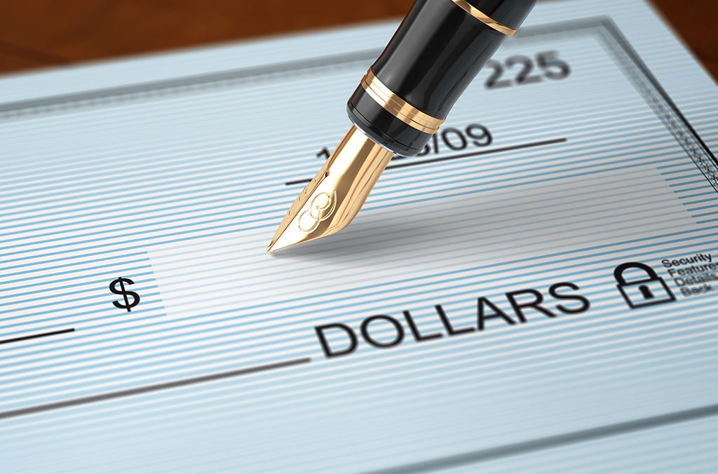 Close-up of a fountain pen poised over a blank check, ready to write an amount in dollars.