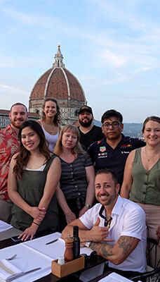 A group of people posing for a photo with the Florence Cathedral (Duomo di Firenze) in the background.