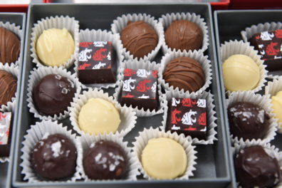 Box of assorted gourmet chocolates, including dark, milk, and white truffles, with square pieces decorated with the Washington State University cougar logo