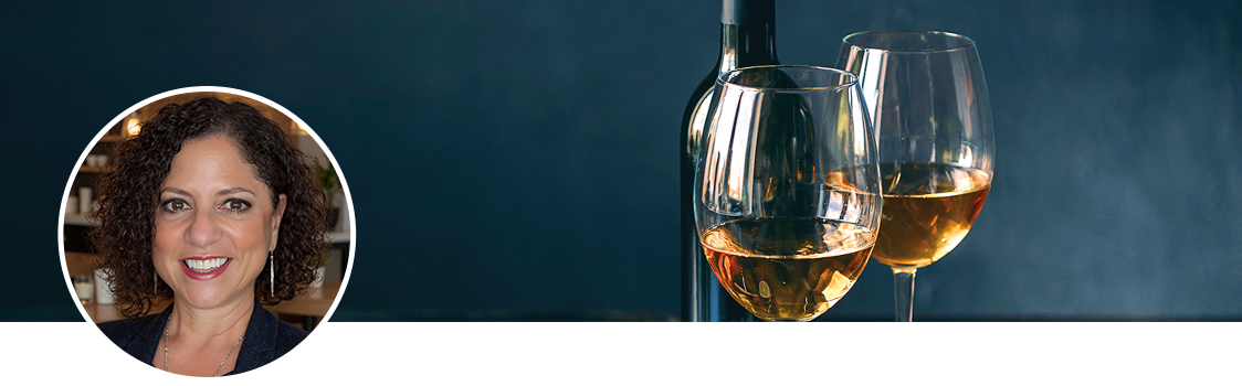 Headshot of Jamie Peha next to two glasses of white wine and a wine bottle against a dark background.