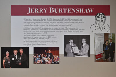 Wall display honoring Jerry Burtenshaw’s legacy in hospitality education, featuring a large title, biographical text, and several photos of events and awards.