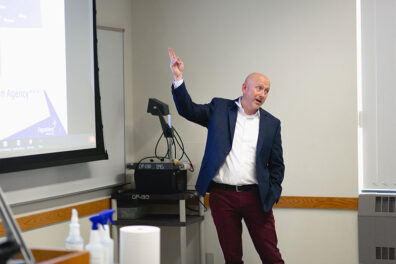 Shawn Petrie of PayneWest Insurance gestures toward a projected slide while discussing sales careers in the insurance industry.