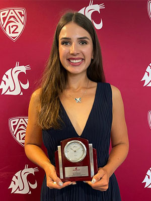 Kateryna Maistrenko holding an award plaque in front of a crimson backdrop with WSU and Pac‑12 logos.