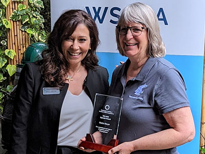 Marla Meyer, at right, holding her award while standing beside Kimberly Scott in front of a Washington Society of CPAs backdrop.