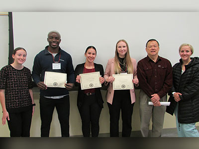 Sophia Sullivan-Pollard, Kenneth Dinyuy, Soho Divers, Kayla Carter, Professor Bernie Wong-on-Wing, and Anna-Maria Rehwaldt standing together holding award certificates.