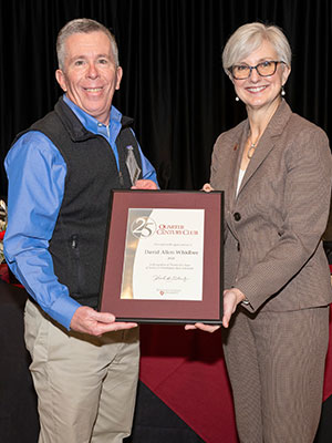 David Whidbee and Chancellor Elizabeth Chilton stand together holding a framed service award during a recognition event.