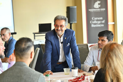 Michael Nassirian leans forward while speaking to participants at the EMBA Leadership Conference 2022, discussing passion and purpose at work as attendees listen around the table.