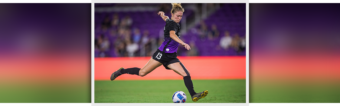 OMBA student Celia Jimenez Delgado in a soccer uniform runs forward on the field, preparing to strike the ball during a match.