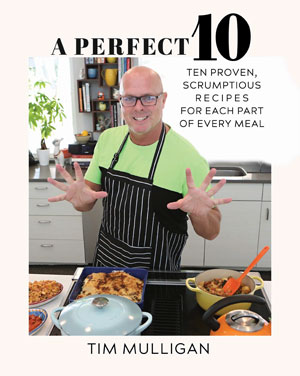 Cover of Tim Mulligan’s A Perfect 10, showing him in a kitchen wearing a green shirt and apron, gesturing over several prepared dishes on the counter.