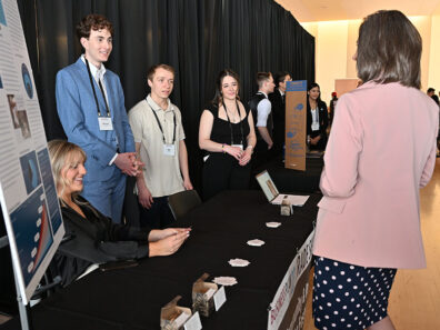 CARE mobile app creators stand behind their booth, speaking with a judge across the table during the competition’s trade show portion.