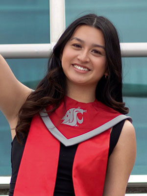 Mackenzie Mosca raises an arm while wearing a WSU graduation stole in red and gray.