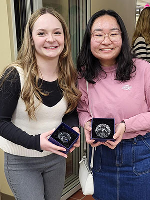 Madeline Mickas and Tu Le display their awards at a hospitality business graduation celebration.