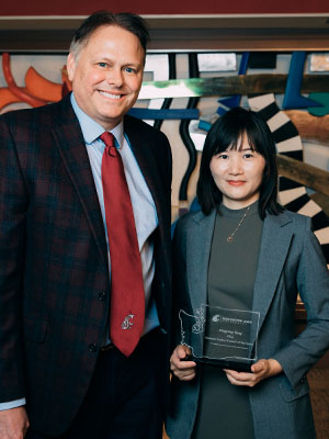 Chuck Munson stands beside Pingping Tang, who holds her 2024 Women of Distinction award.