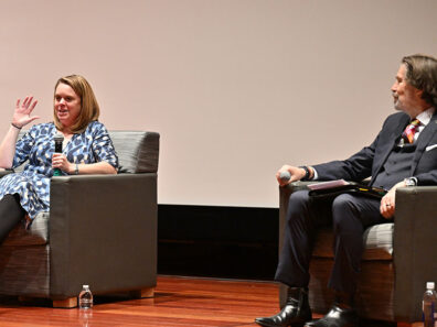 Alum Jaimie Jacobsen and Professor Joe Compeau sit on stage in armchairs, speaking at the fall 2024 Business Technology Symposium.