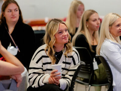 Students sit in a group listening to alumni and industry leaders during the spring 2024 Women in Business Networking Luncheon.