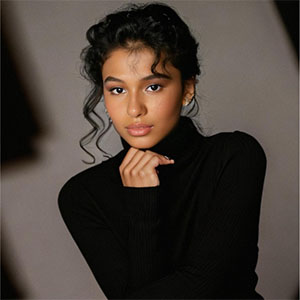 Meredith Sanders in a black turtleneck posed against a softly lit background.