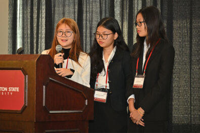 Three CamEd Business School students from team 'Ompovision' present at the 2025 Marketing and International Business Symposium at Washington State University.
