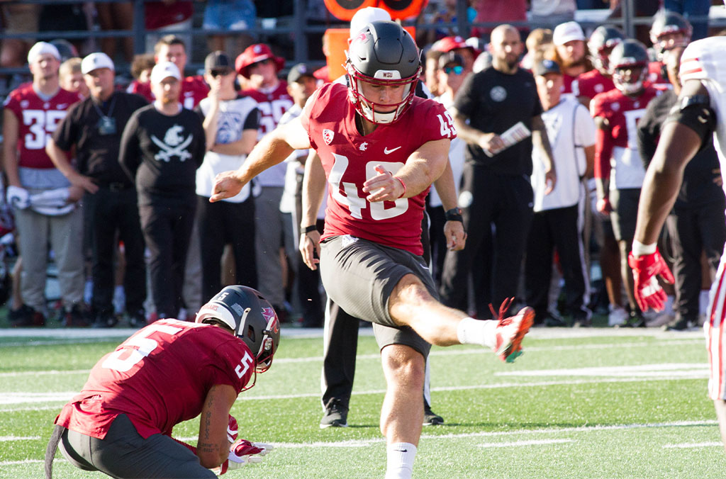 Dean Janikowski, wearing jersey number 46, kicks a football during a game.