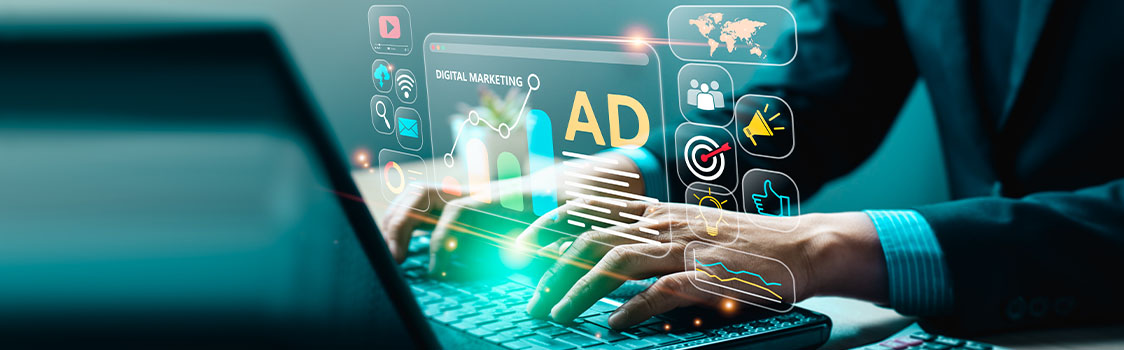 Hands typing on a laptop with holographic icons for digital marketing, advertising, analytics, and social media displayed above the keyboard.
