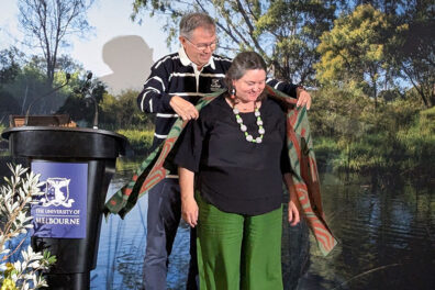 Professor Joseph Gladstone placing a patterned shawl on Dilin Duwa Centre Director Michelle Evans during the Dialogues at the University of Melbourne.