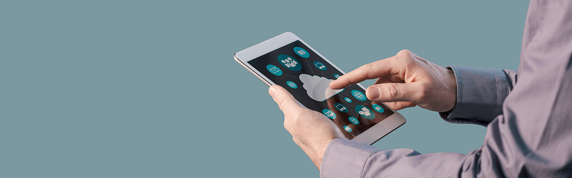 Hands use a tablet displaying cloud and mobile app icons, representing digital technology and app development.