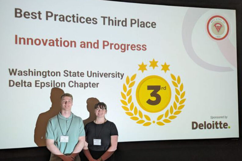 Henri Holtrop and Victoria Petersen stand before a presentation slide recognizing WSU’s third-place finish in the Beta Alpha Psi Innovation and Progress competition.
