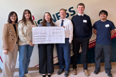Pingping Tang stands with the Fastenal Case Competition winners as they display an oversized prize check in front of a CWU backdrop.