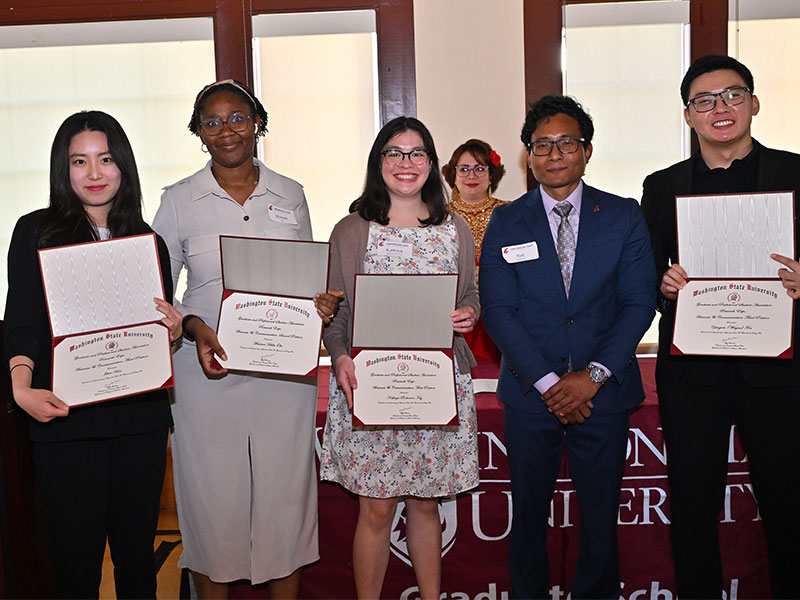 Six individuals standing in a row holding certificates at a WSU event. Mariam Hilda Ola is second from the left, and Yingwei (Wayne) Xu is on the far right.