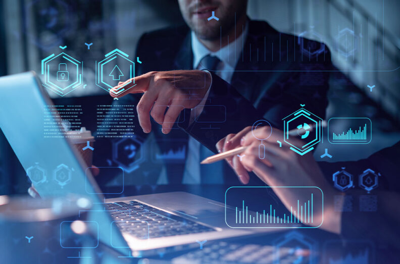 Two people collaborating at a desk with a laptop, pointing at the screen. Digital graphics of data charts, security icons, and upload symbols are overlaid, representing technology and analytics.