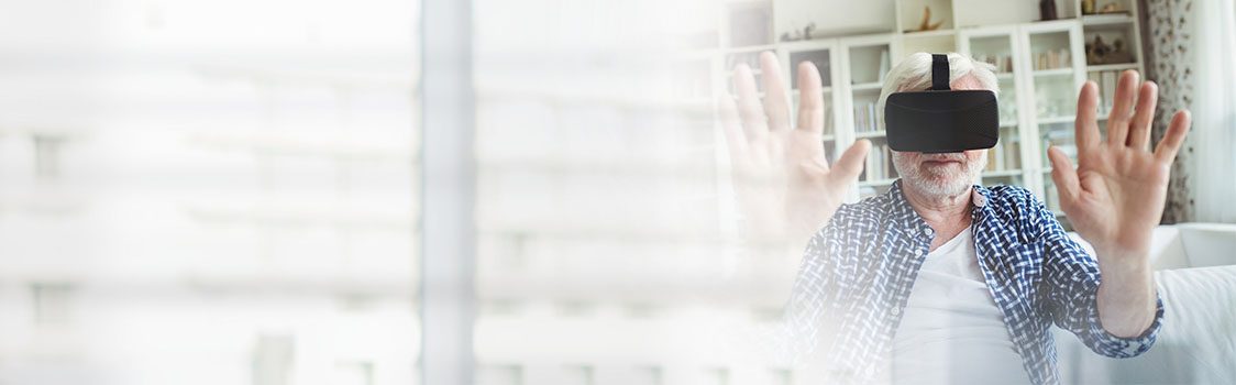 Person wearing a virtual reality headset with hands raised, sitting in a bright living room with shelves in the background, representing immersive VR experience.