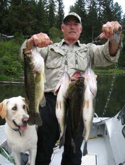 William Andrefsky with his dog in a boat holding a catch of four fish.