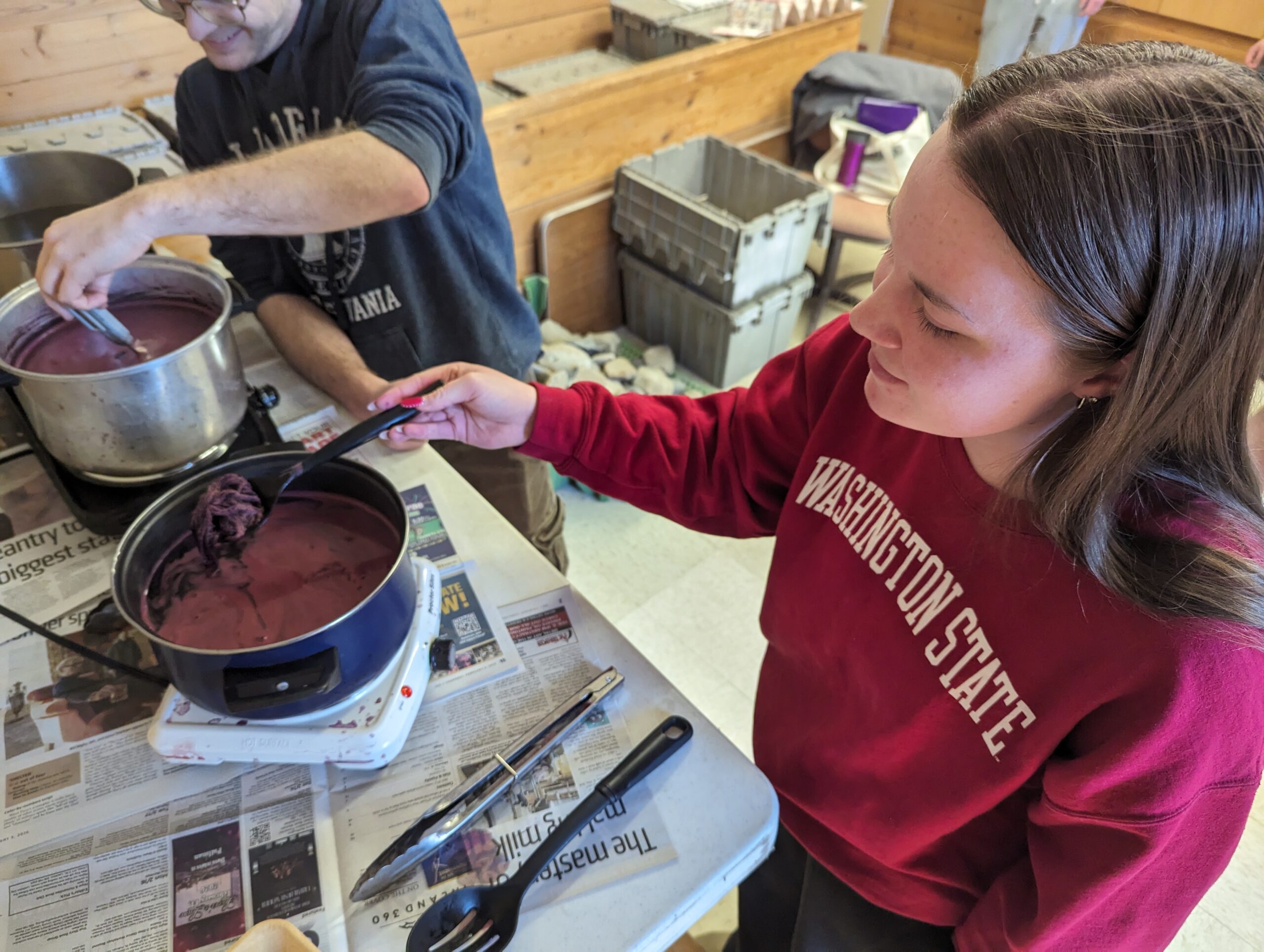A student soaks yarn in the cochineal dye
