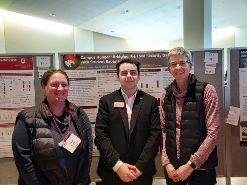 Androu Luzader presents a poster with Sarah Whitley and Julie Kmec
