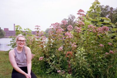 An image of Michaela Mcparland in front of a flowery bush