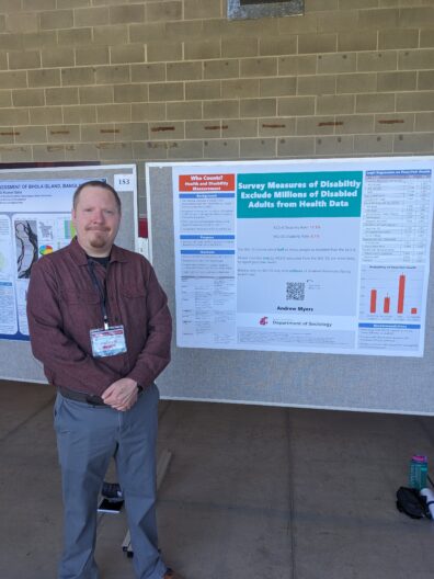Andrew Myers standing next to his research poster