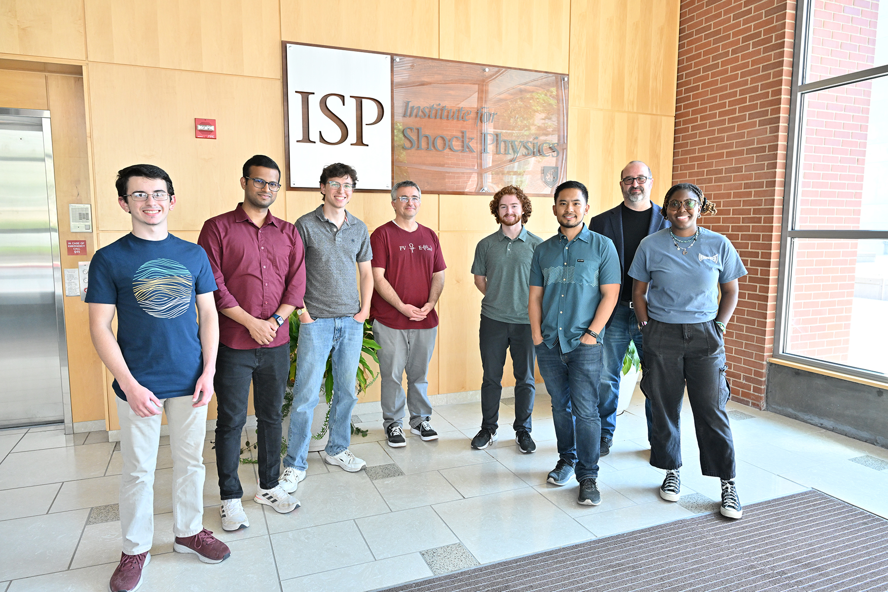Group of students and instructor standing in front of ISP building sign.