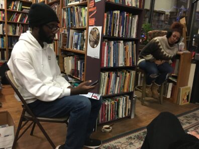 Two people in library, sitting and reading poetry. 