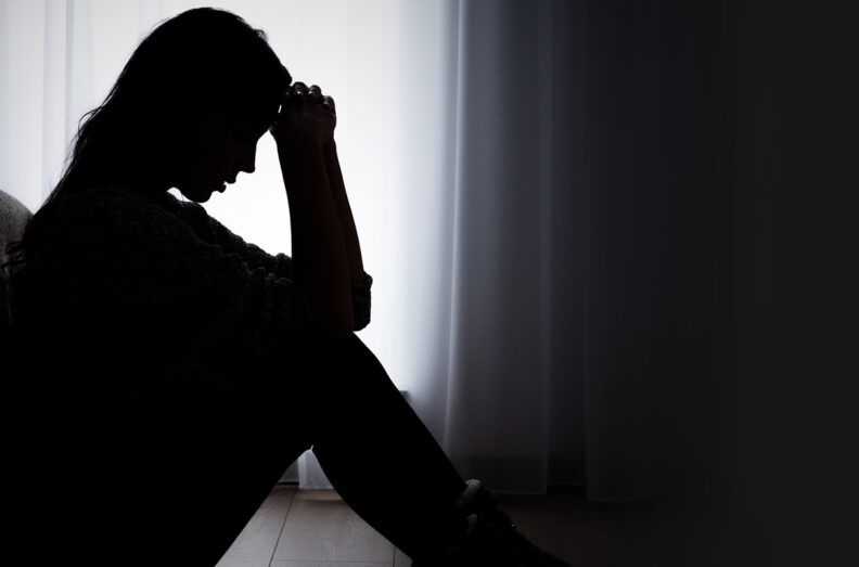 A woman sits hunched over having a panic attack.
