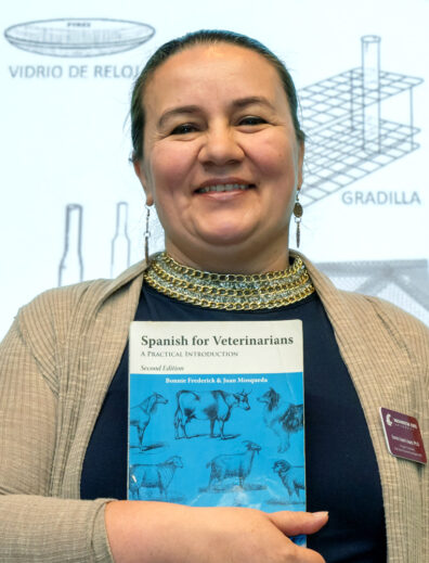 Sonia Lopez-Lopez holding a textbook titled "Spanish for Veterinarians."