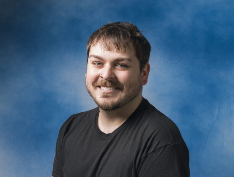 Keegan Baatz headshot with blue backdrop