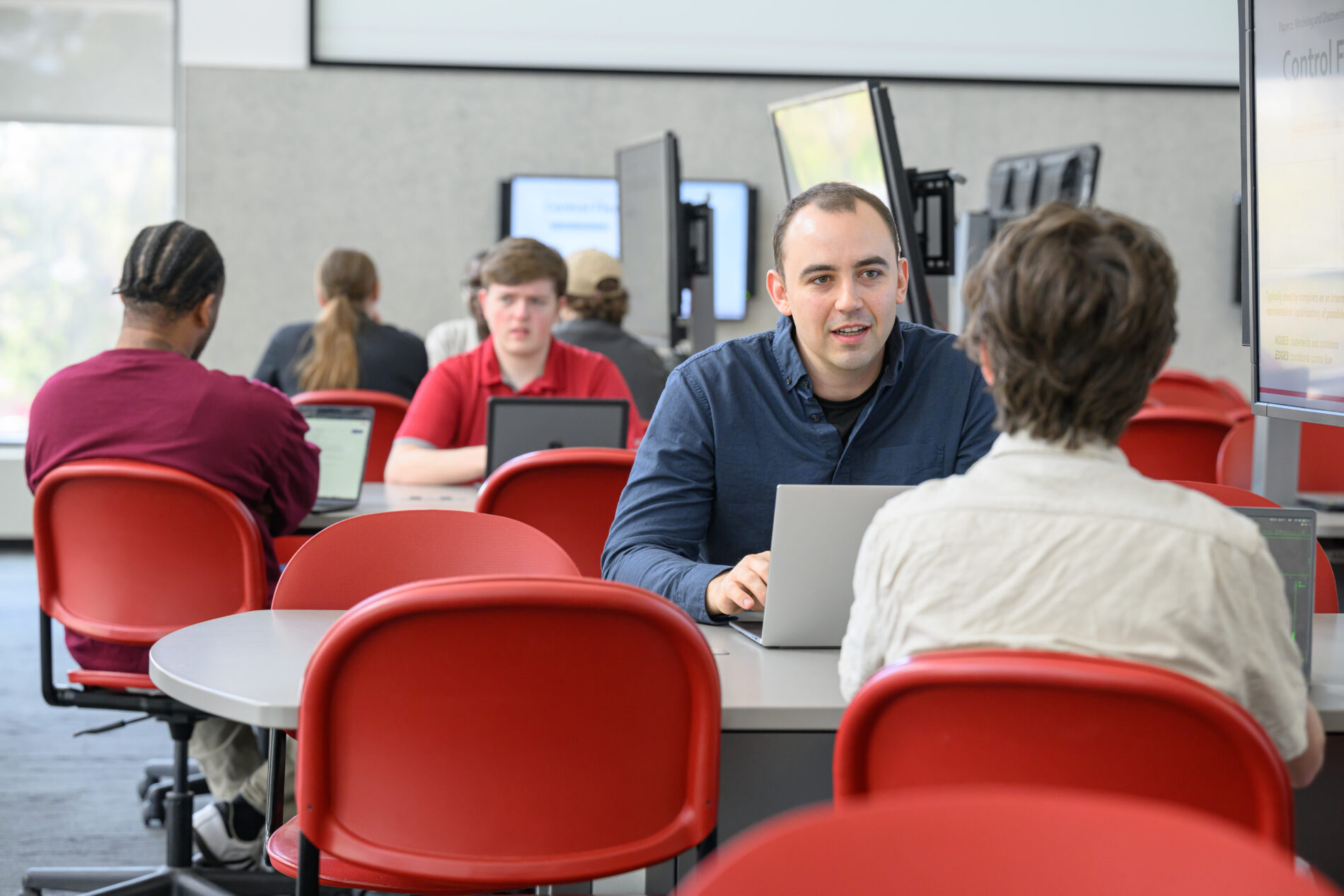 Students meeting and working at laptops in a common area.