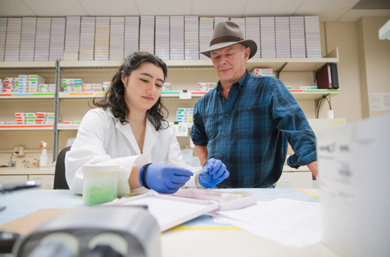 Sarah De Santos and Michael Skinner working together in a laboratory.