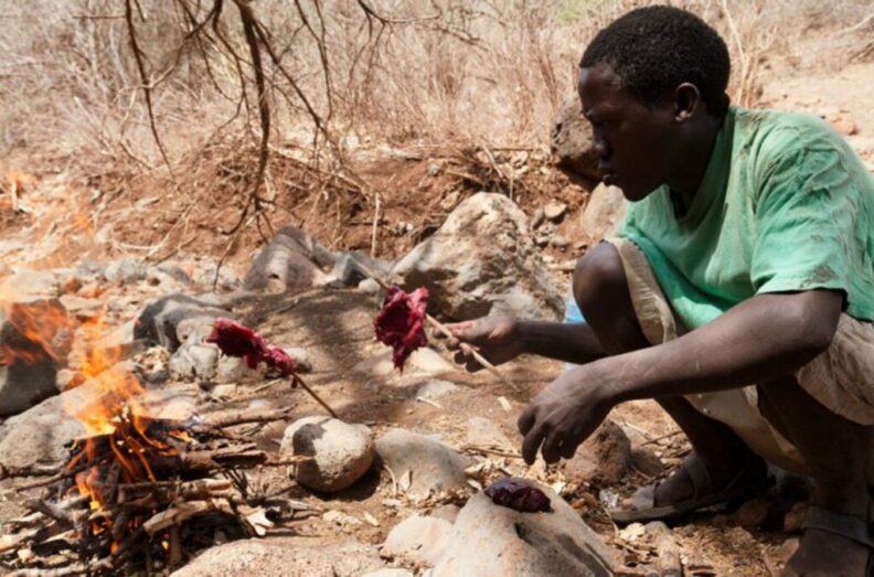 A Hadza man in Tanzania cooks over an open fire.