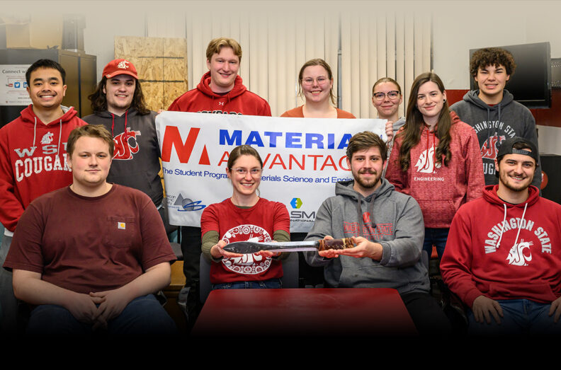 Members of the WSU Material Advantage Club holding a club banner and showcasing a sword that they made.